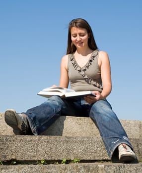 girl reads book with sky at background
