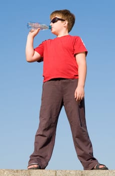 boy drinks water on a blue sky