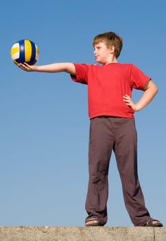 little boy with volleyball ball on a blue sky