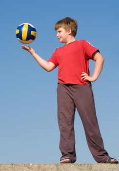boy throws volleyball ball on a blue sky