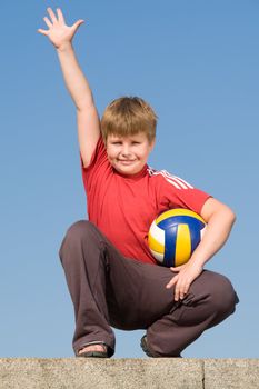 Greeting. Boy with volleyball ball on a blue sky