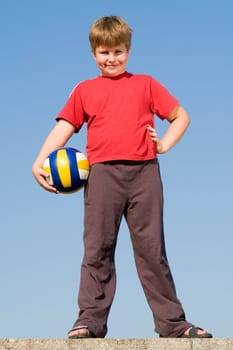 little boy with volleyball ball on a blue sky