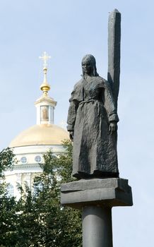 Statue. woman near a column with church at background