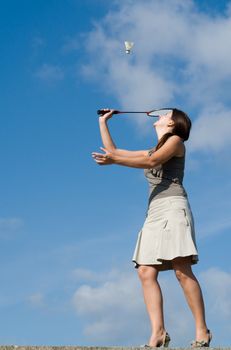 young woman playing badminton on a blue sky