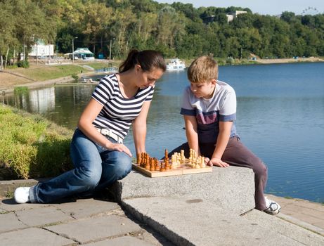 Mum and the son play a chess in park