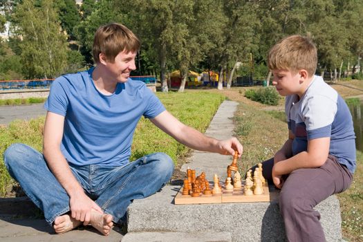 Father playing chess with his boy in park