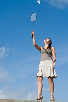 young woman playing badminton on a blue sky