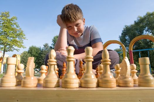 little boy play a chess in park