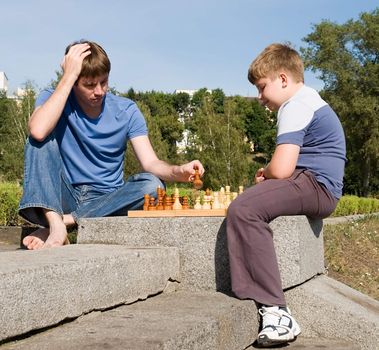 Father playing chess with his boy in park