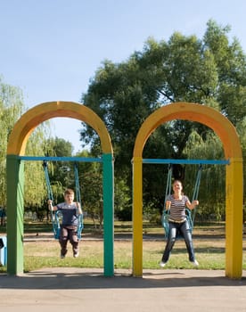 Mum and the son on a swing in city park