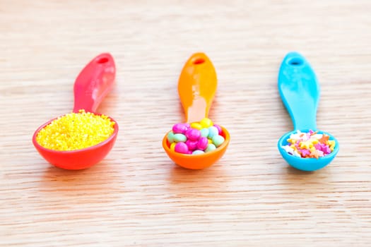 Three colorful plastic measuring spoons with cake decorations