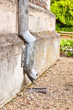 A drain pipe against an old stone wall