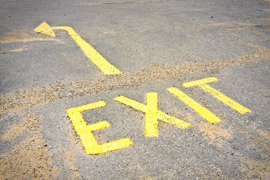 Yellow exit sign on a tarmac surface