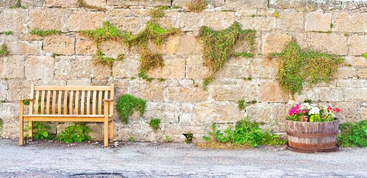 A wooden bench in front of a stone wall