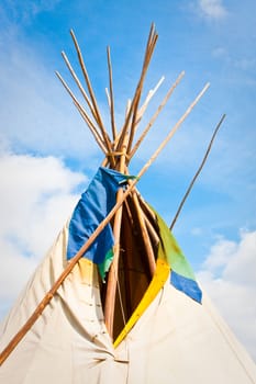 Top of a traditional wigwam against a bright blue summer sky