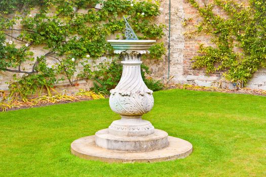 An ornate sundial in a traditional english garden