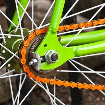 Close up image of a vibrant bicycle wheel with an orange chain