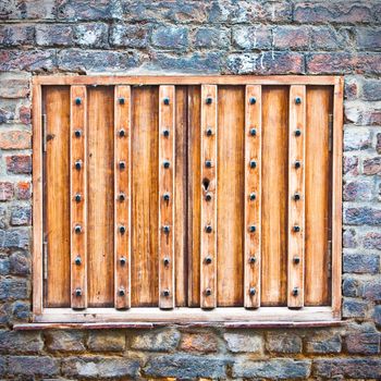 Old studded wooden shutters in a brick wall with cold tones