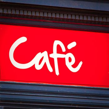 A quirky cafe sign in white writing on red background