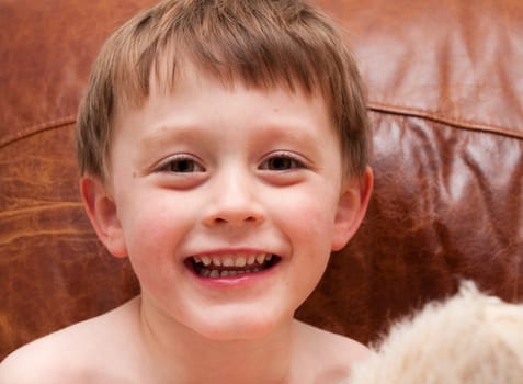 A cheerful young child sitting on a leather sofa at home