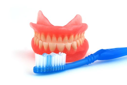dentures and toothbrush on white background
