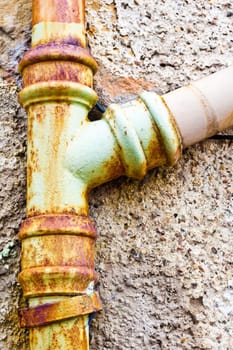 A rusty drainpipe against a stone wall