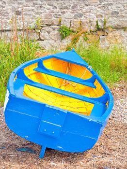 Brightly colored rowing boat moored on a pebble beach