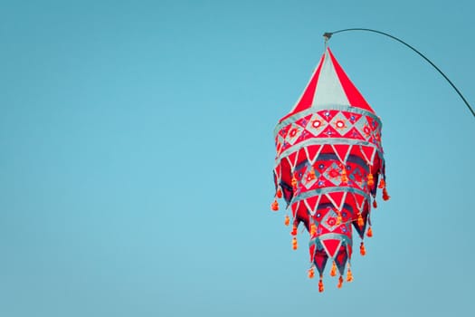 A nice red lantern hanging against a bright blue sky with ample copyspace