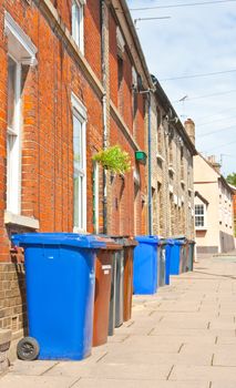 Row of plastic wheely bins outside terraced houses in England