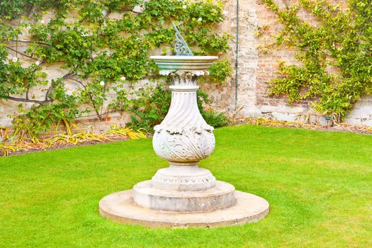 An ornate sundial in a traditional english garden