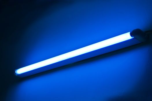 One fluorescent lamp shining on blue colored wall