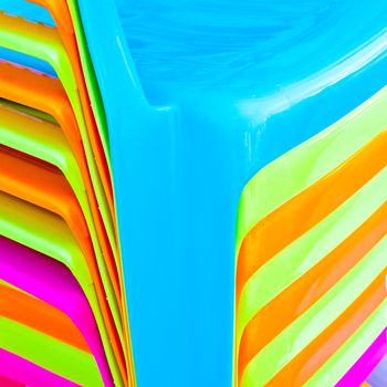 A close up image of stacked plastic chairs as a colorful background