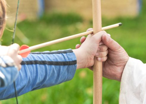 Close up of a child being taught archery