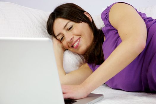attractive woman reads happy her laptop laying in bed