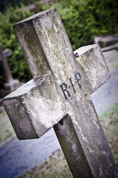 Old stone grave cross in cold lighting