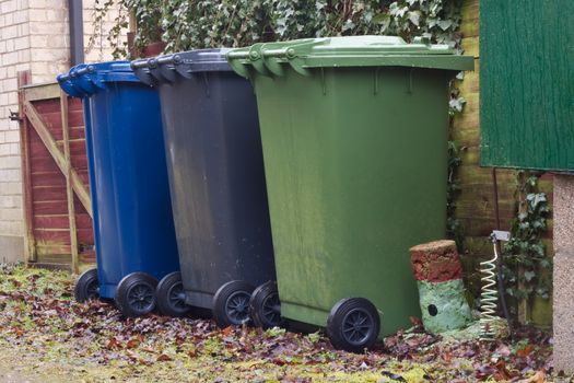 three plastic wheely bins