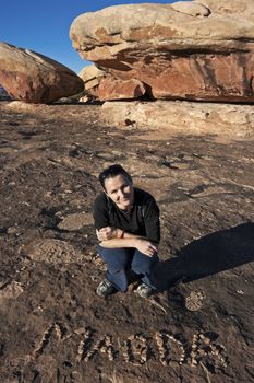 Smiling girl with her name written with little stones. Canyonlands National Park, Utah, USA.
