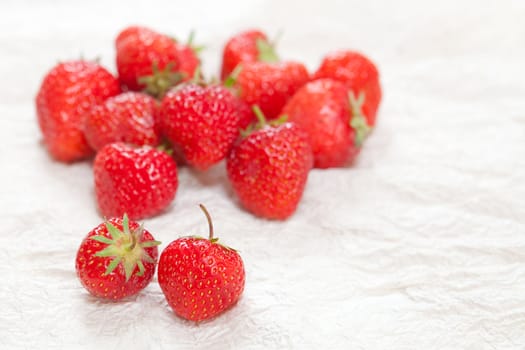 Fresh ripe strawberries on a crinkled white surface