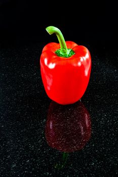 A perfect red bell pepper reflected in granite