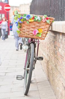 A lady's pedal bike with a colorfully decorated basket