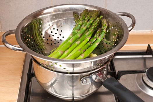 Fresh asparagus being steamed in a colander