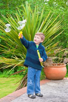 Young boy playing with bubbles outside in a garden