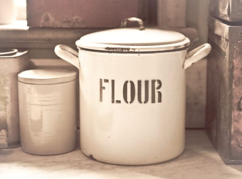Vintage toned image of an enamel flour tin in an old style kitchen