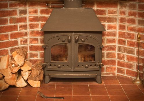 A wood burning stove in a red brick fireplace