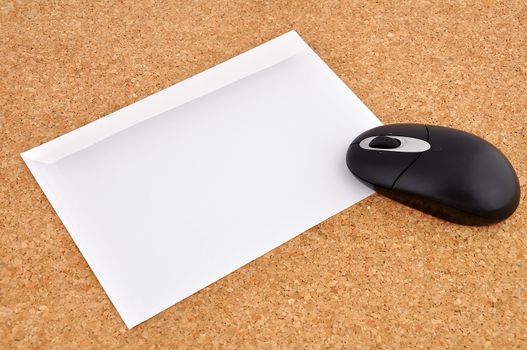 wireless mouse and an envelope on the cork background