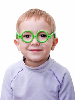 Little spectacled child smiling in green toy glass