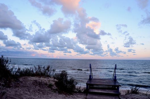 Stairs in dunes and sea view. Natural sea and cloudy sky background.