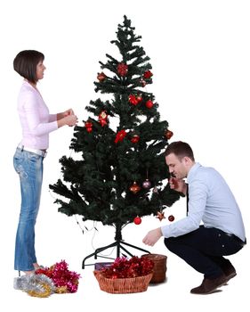 Studio shot of a young couple decorating the Christmas tree against a white background.