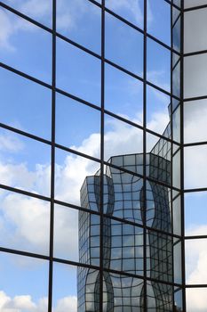 Glass and steel building reflected in glass wall