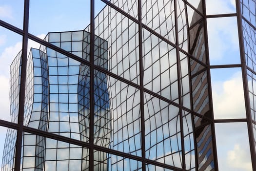 building of glass and steel and clouds reflected in glass facade

